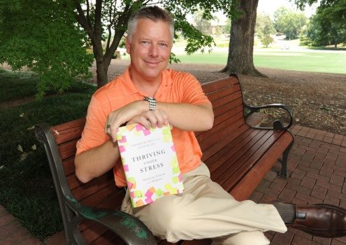 Tom Britt on a bench with his book