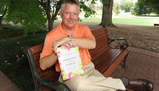 Tom Britt on a bench with his book