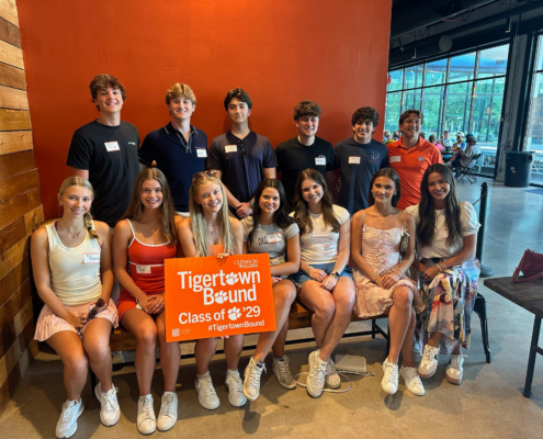SSO-2 group of new students standing and sitting posing for photo in front of an orange wall